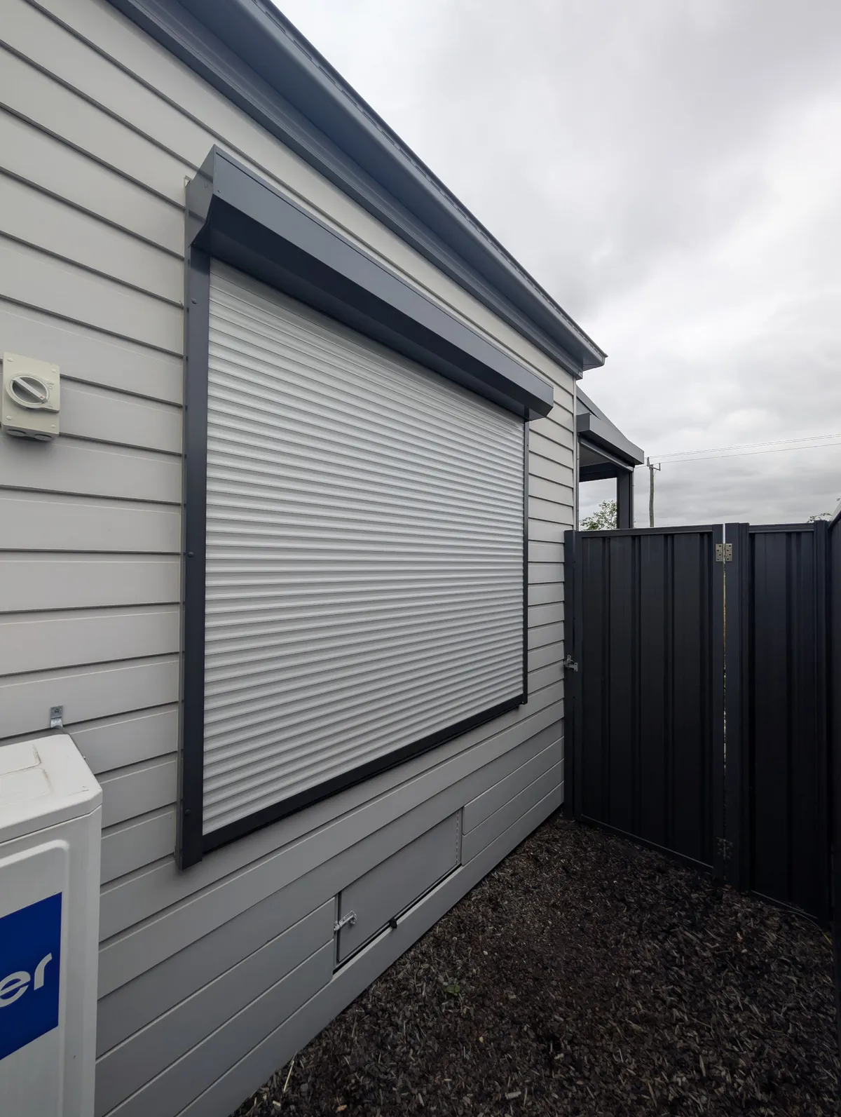 Closed roller shutter on the side window of a weatherboard home, viewed at an angle