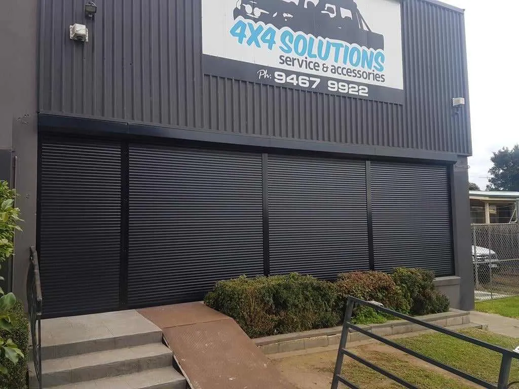 Black roller shutters closed across the ground-floor frontage of a 4x4 accessories business