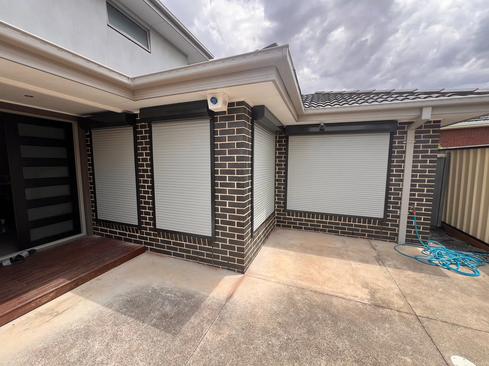 Light roller shutters on windows either side of a dark brick corner