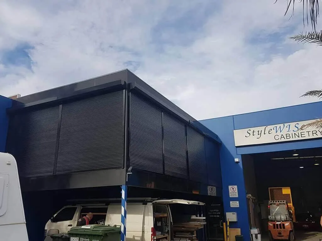 Dark roller shutters on the upper windows of a cabinetry workshop building