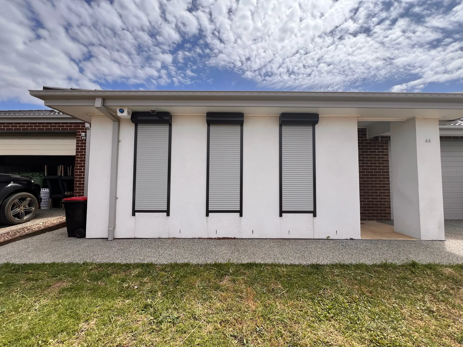 Three narrow roller shutters on the windows of a white rendered house front